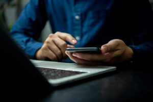 A man is using a cell phone while sitting at a desk