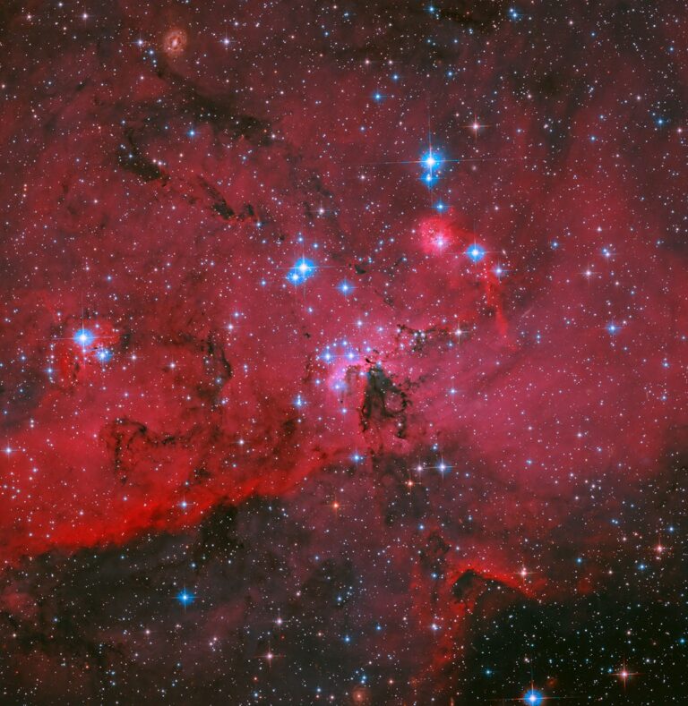 Hubble da NASA captura nuvem vermelha cintilante com estrelas brancas e azuis